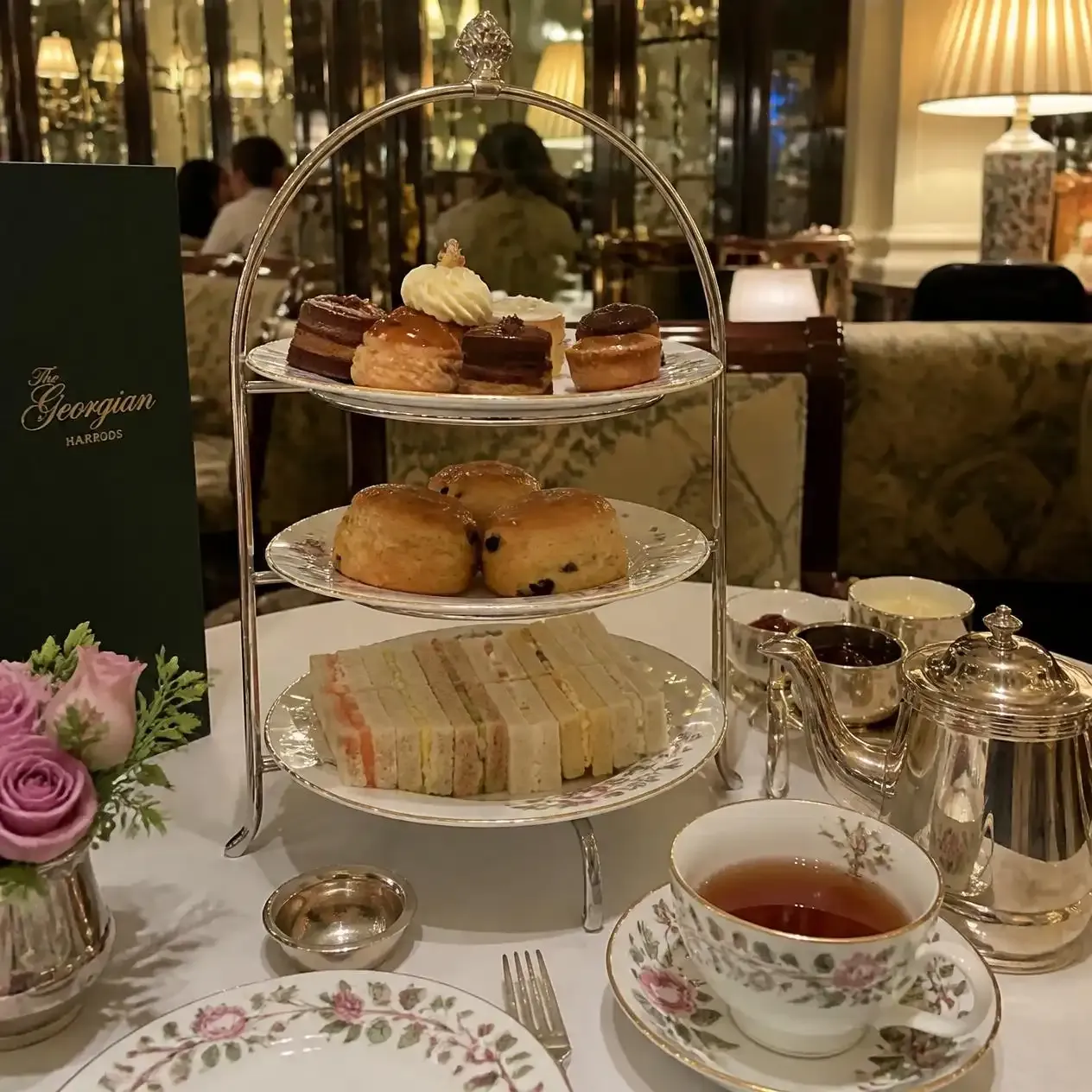 A tiered afternoon tea stand with finger sandwiches, scones and pastries at The Georgian in Harrods, London