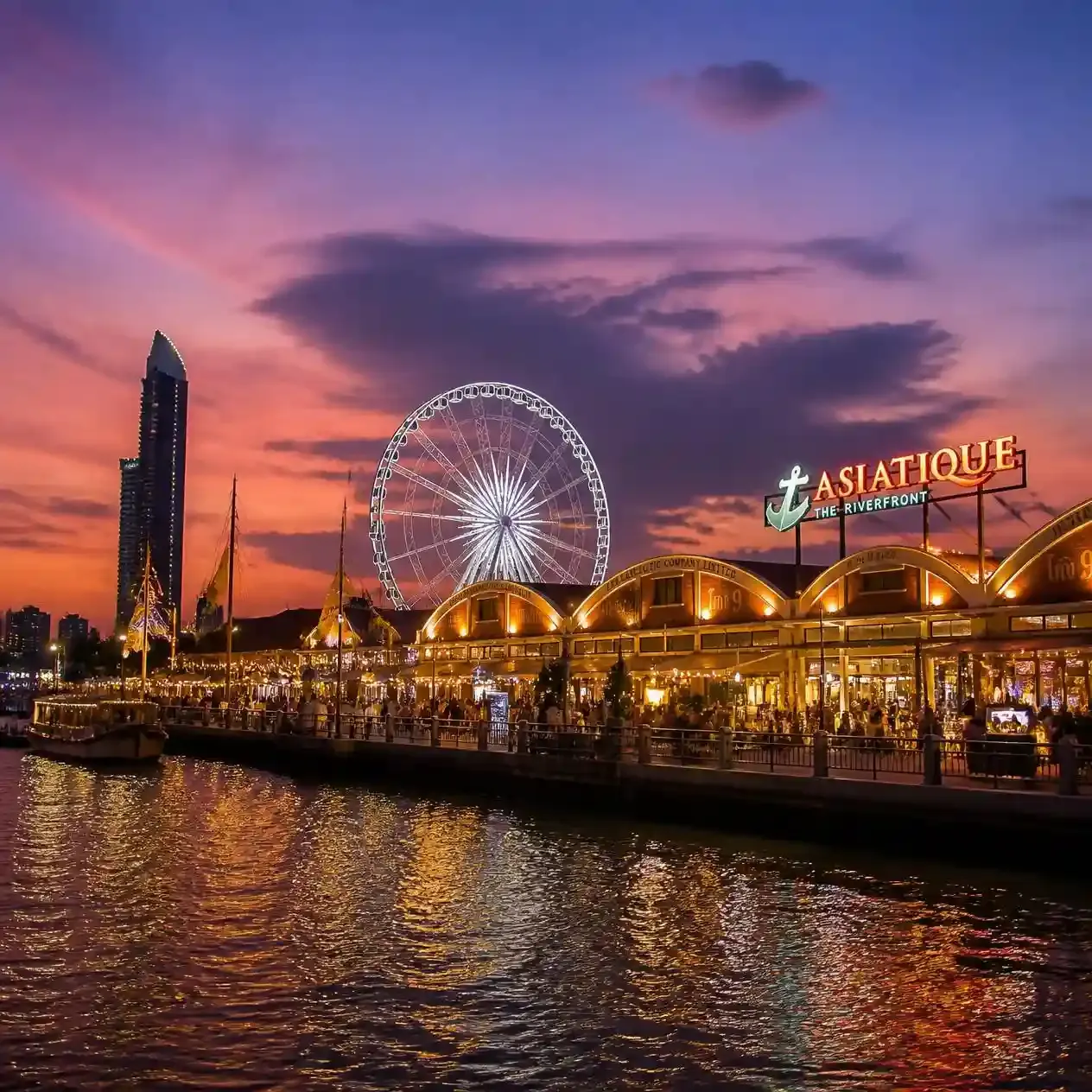 Restored warehouse buildings and the illuminated Ferris wheel at Asiatique The Riverfront on the Chao Phraya River in Bangkok at dusk