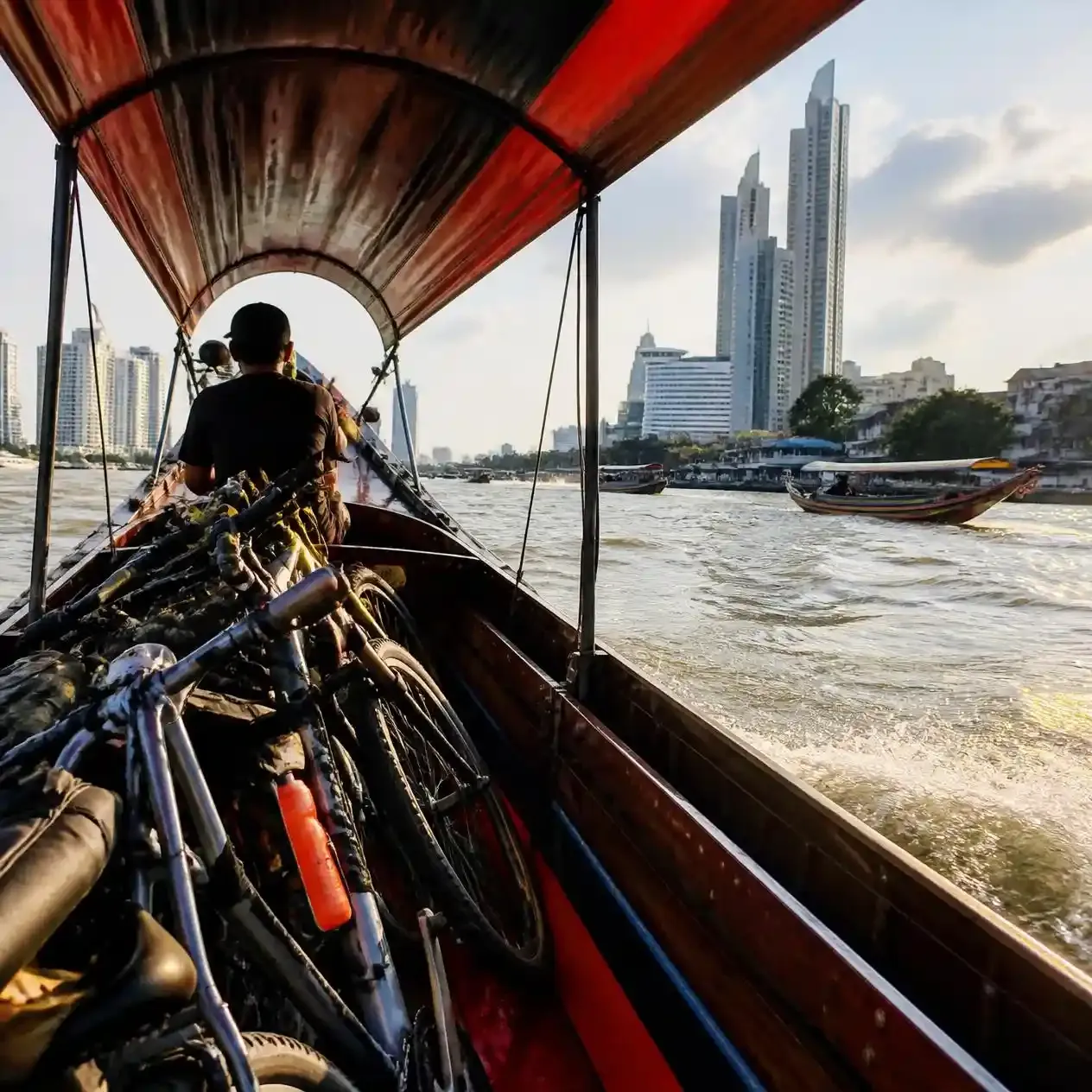 Bicycles loaded onto a wooden longtail ferry crossing the Chao Phraya River towards Bang Krachao in Bangkok