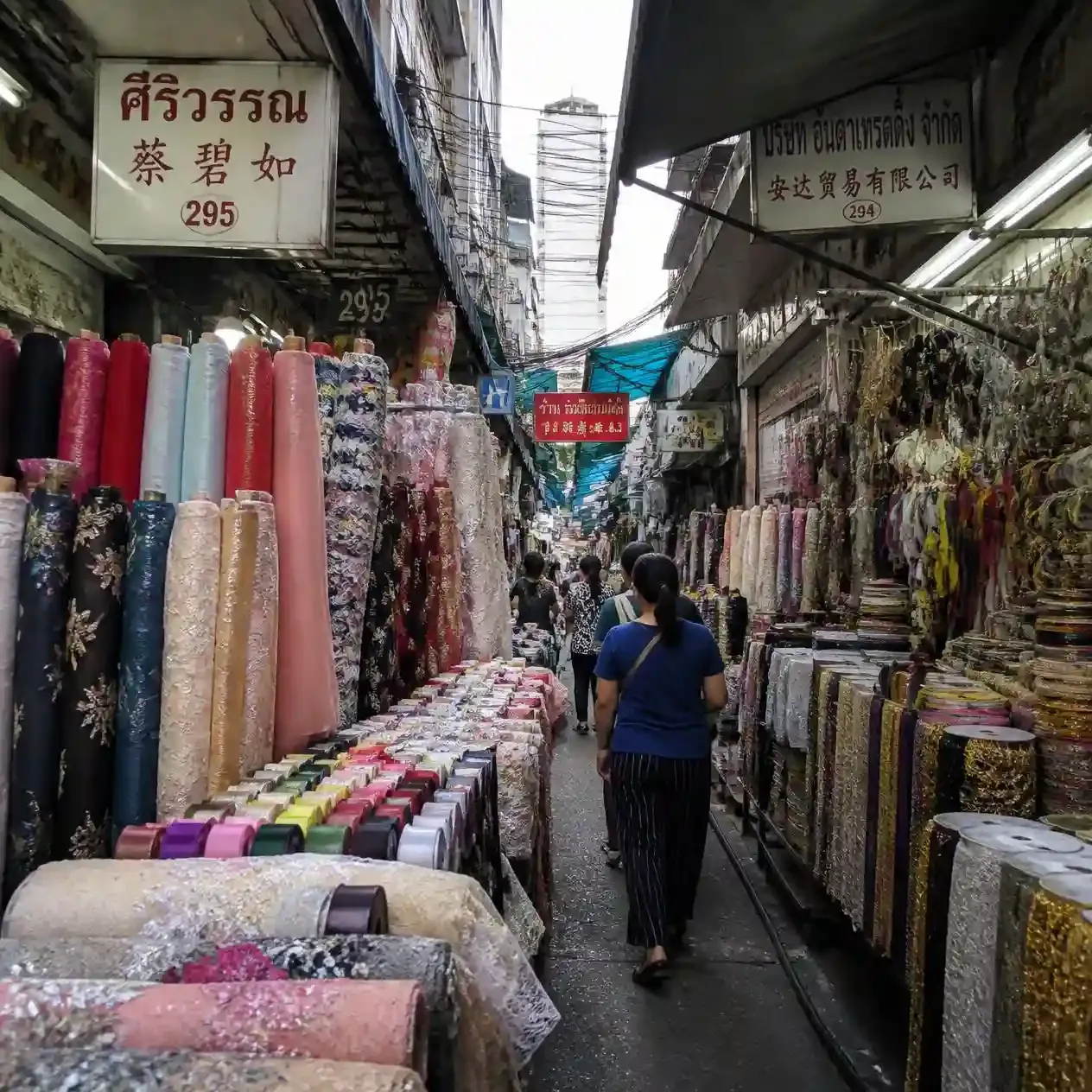 Stacked bolts of fabric and ribbon lining the narrow wholesale alley of Sampeng Lane in Bangkok Chinatown
