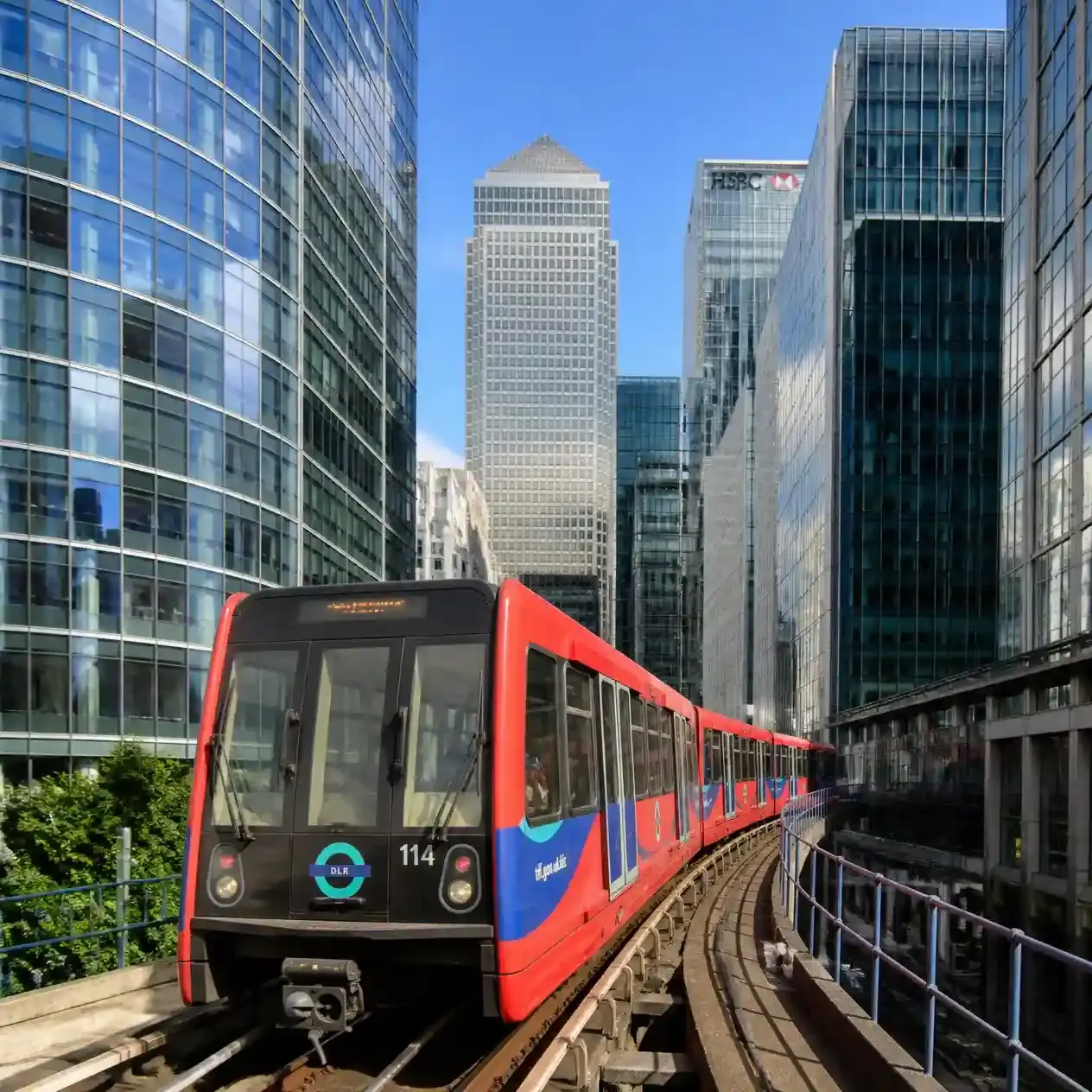 Driverless DLR train crossing the elevated track through Docklands with Canary Wharf towers behind