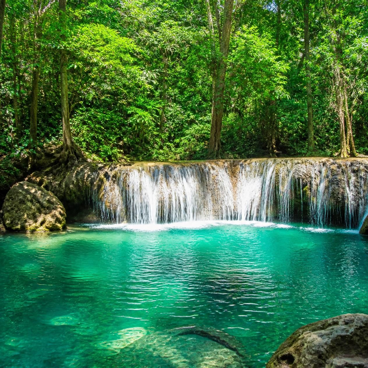Turquoise pool and limestone terraces at an upper tier of Erawan Falls in Kanchanaburi province, Thailand