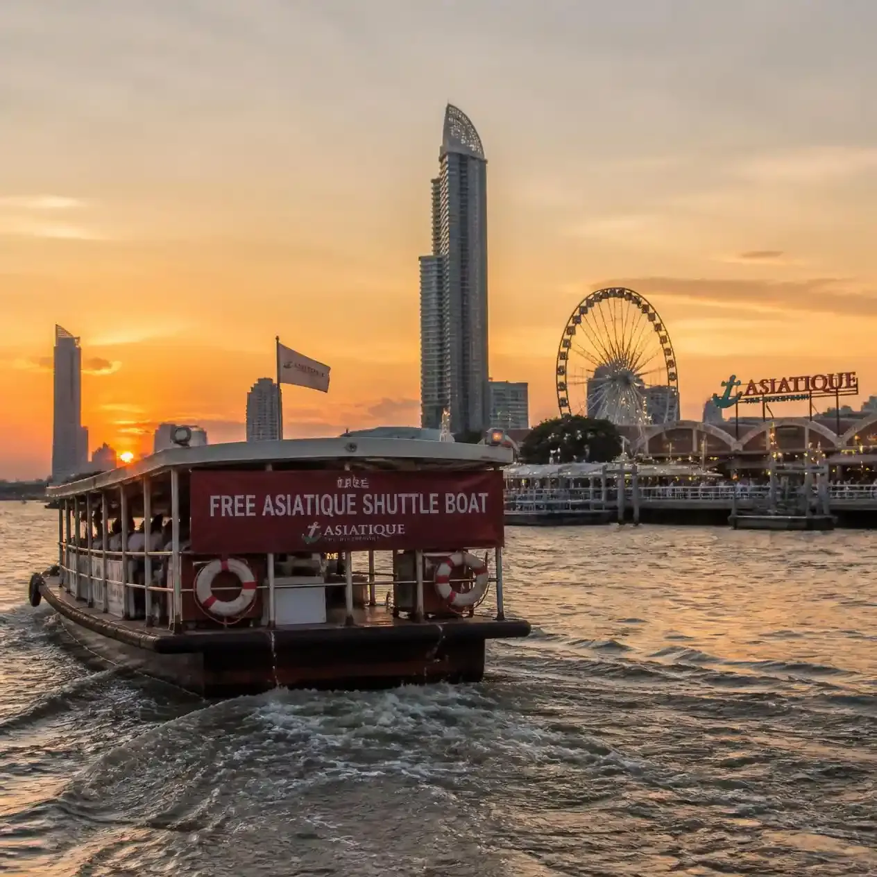 Free Asiatique shuttle boat crossing the Chao Phraya River towards the Asiatique pier in Bangkok in the evening