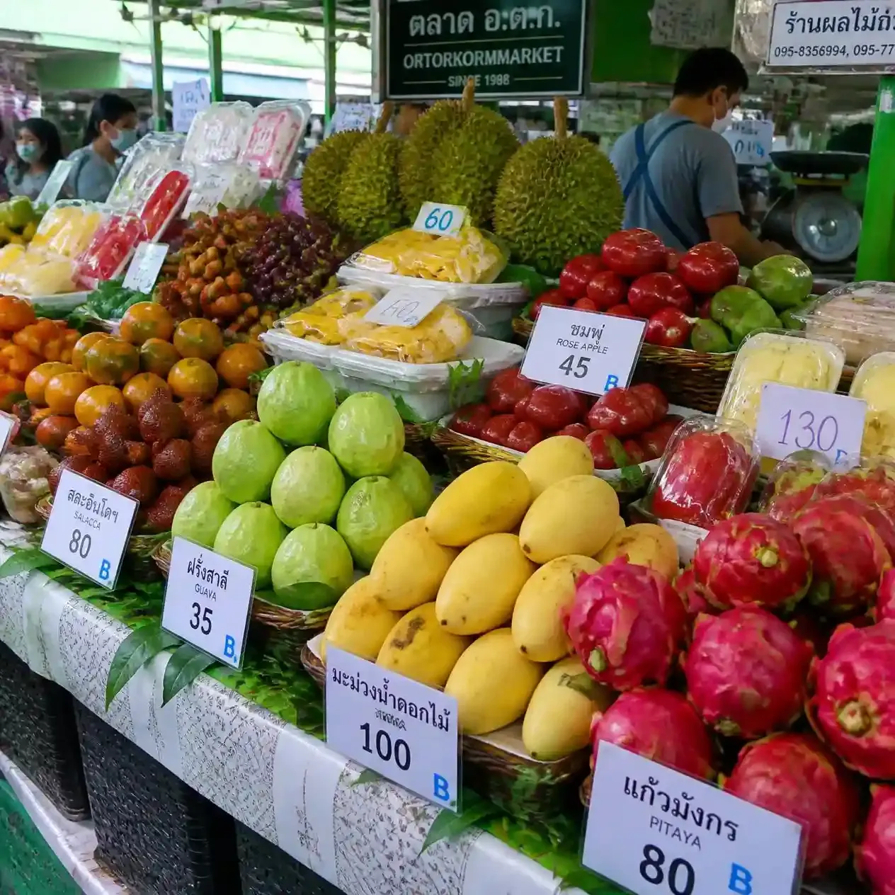 Stacked tropical fruit and fresh produce on display at Or Tor Kor Market during a Bangkok food tour