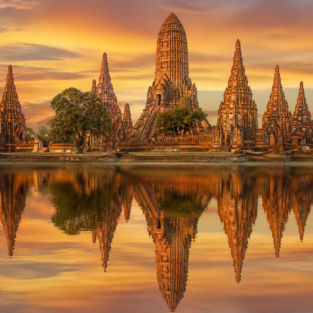 Khmer-style prangs of Wat Chaiwatthanaram reflected in the Chao Phraya river at sunset in Ayutthaya, Thailand