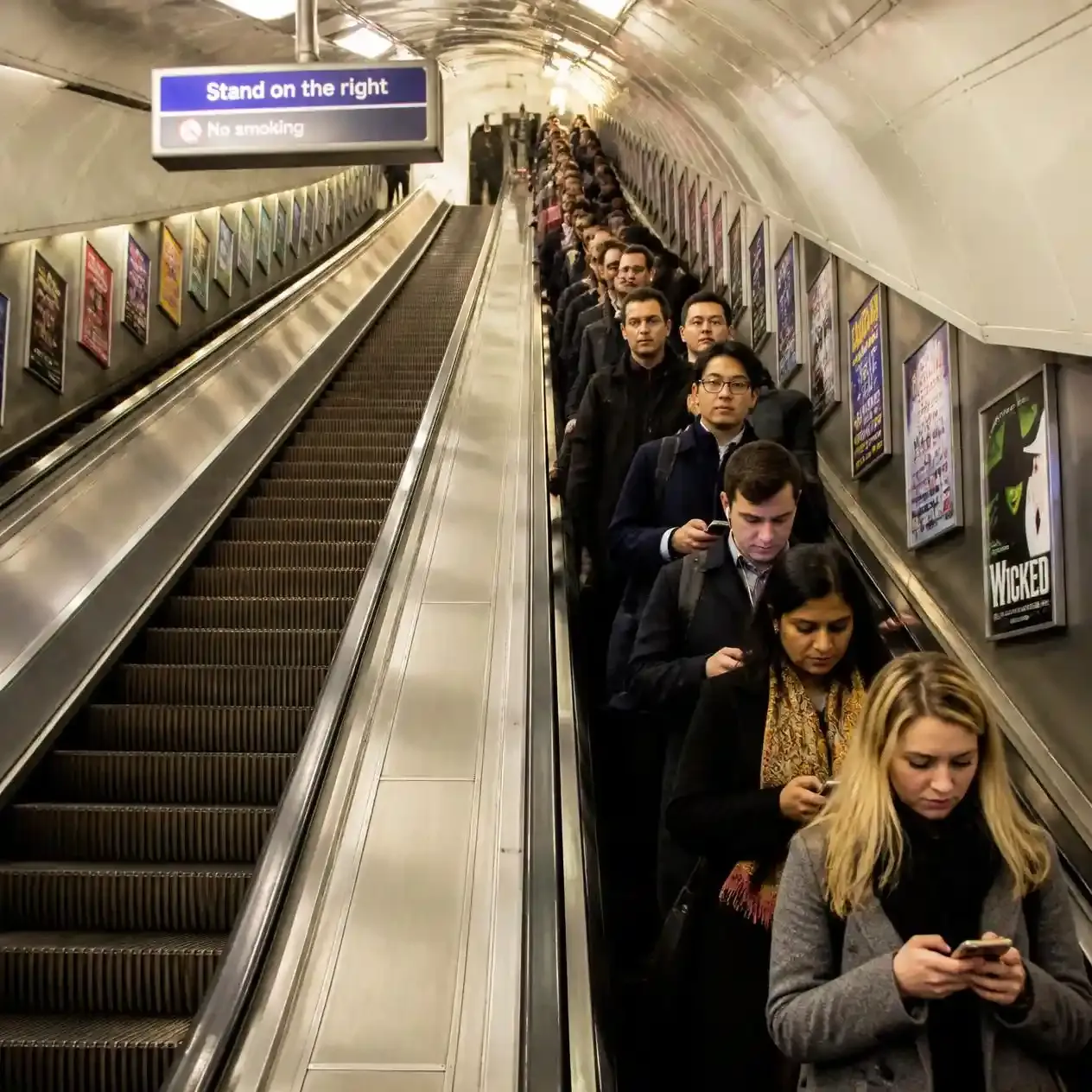 Commuters on a London Underground escalator standing on the right and leaving the left side clear for walking