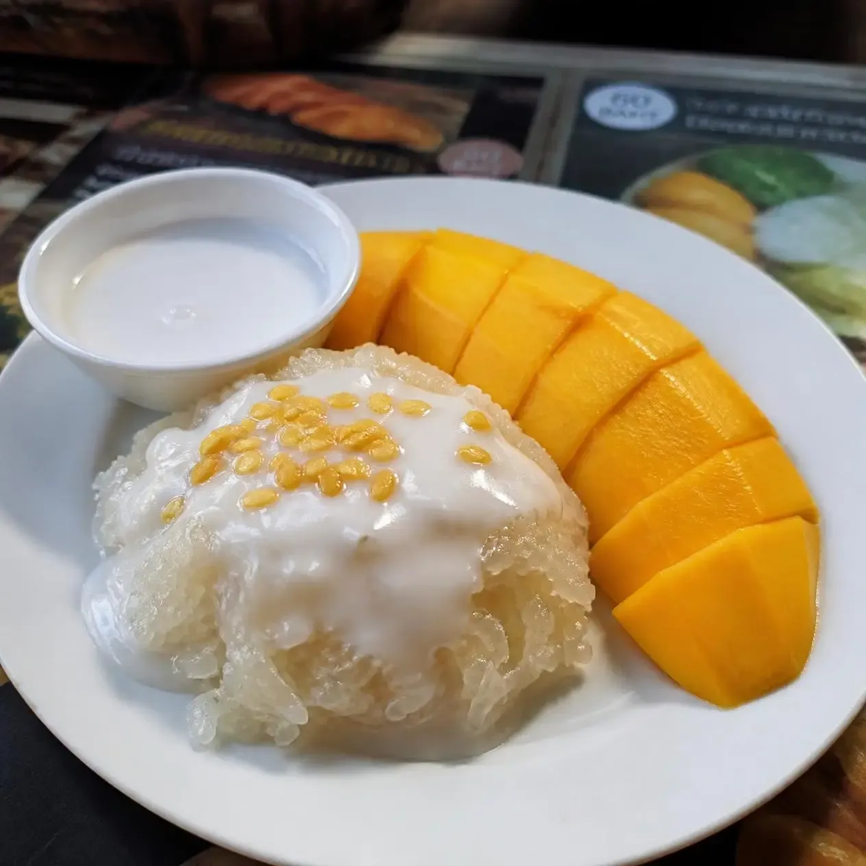 Mango sticky rice served with sliced ripe yellow mango and coconut cream, a classic local food in Bangkok