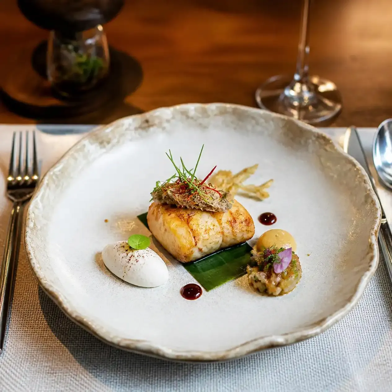 Plated tasting menu course served at a Michelin-starred fine dining restaurant in Bangkok
