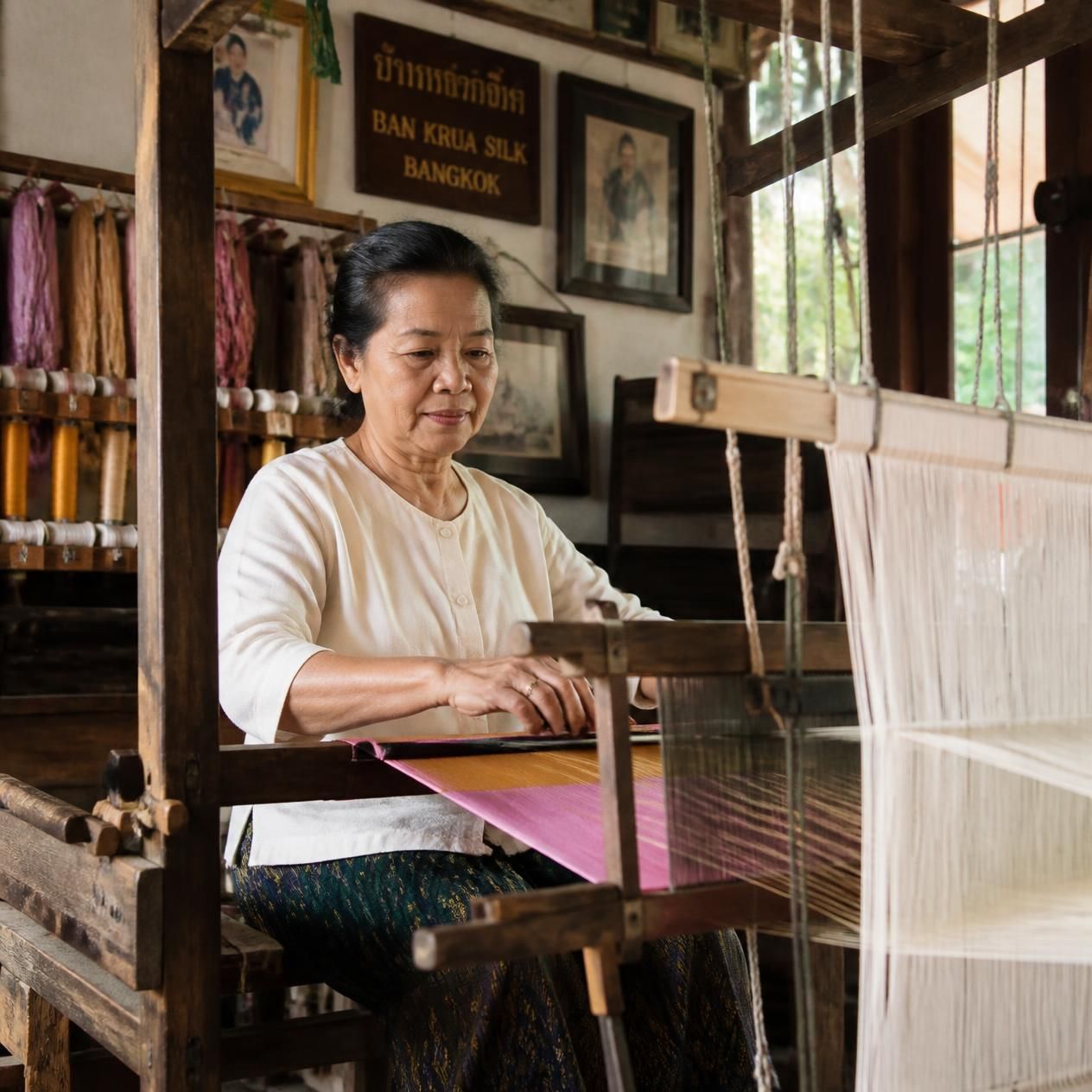 Weaver at a wooden handloom threading coloured silk in the Ban Krua community across the canal in Bangkok