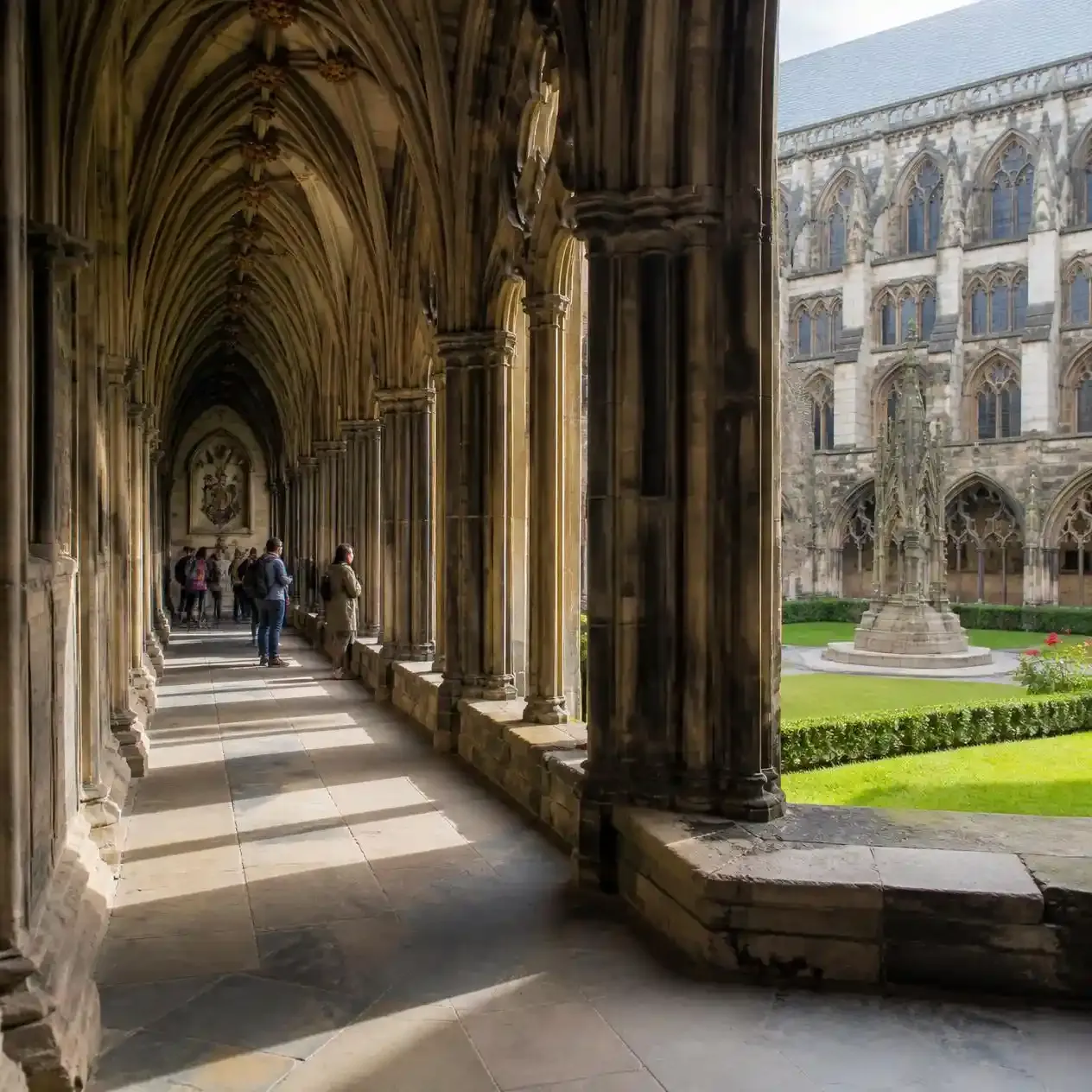 Stone-arched Great Cloister walkway at Westminster Abbey looking onto the green courtyard garth
