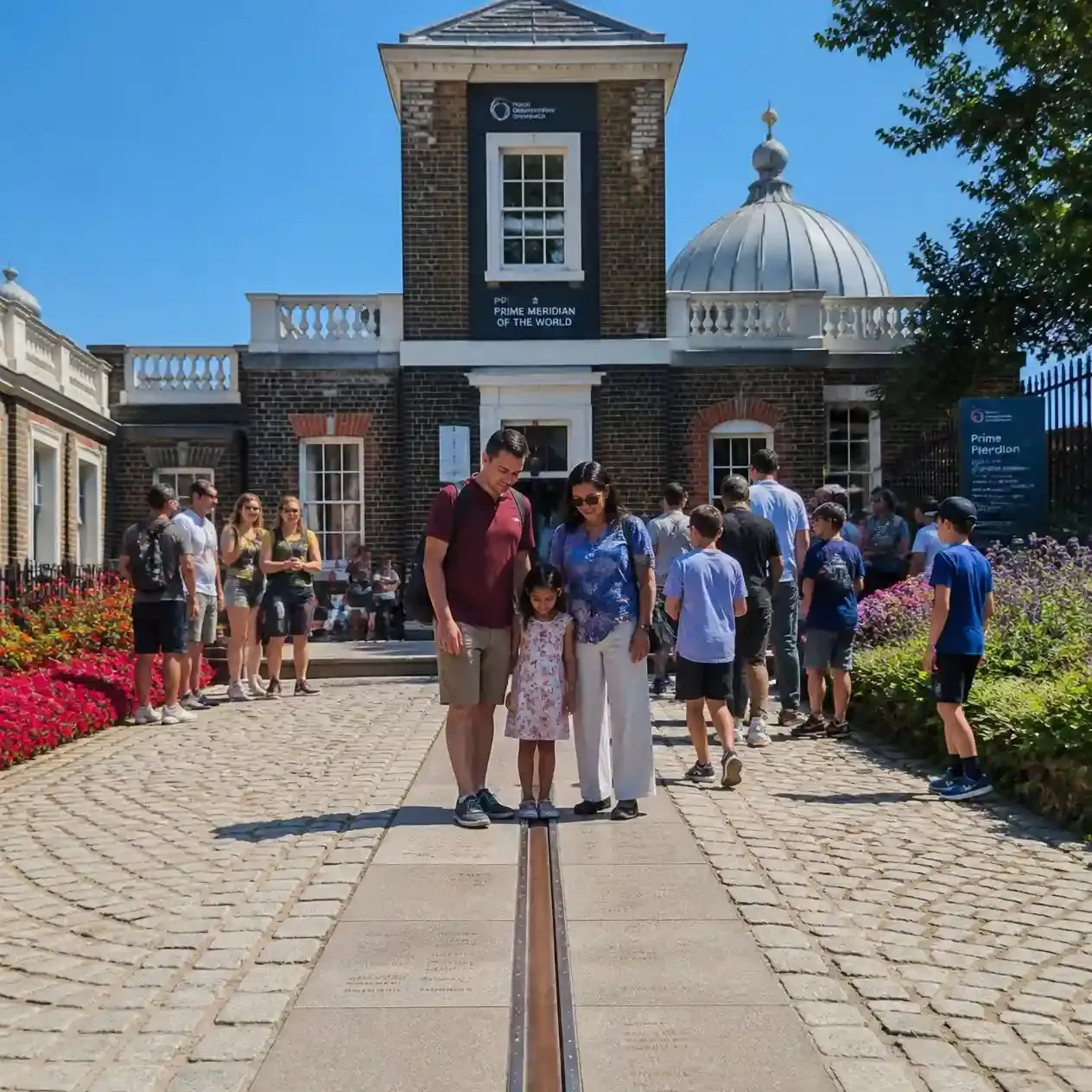 Visitors standing on the Prime Meridian line in the courtyard of the Royal Observatory at the top of Greenwich Park