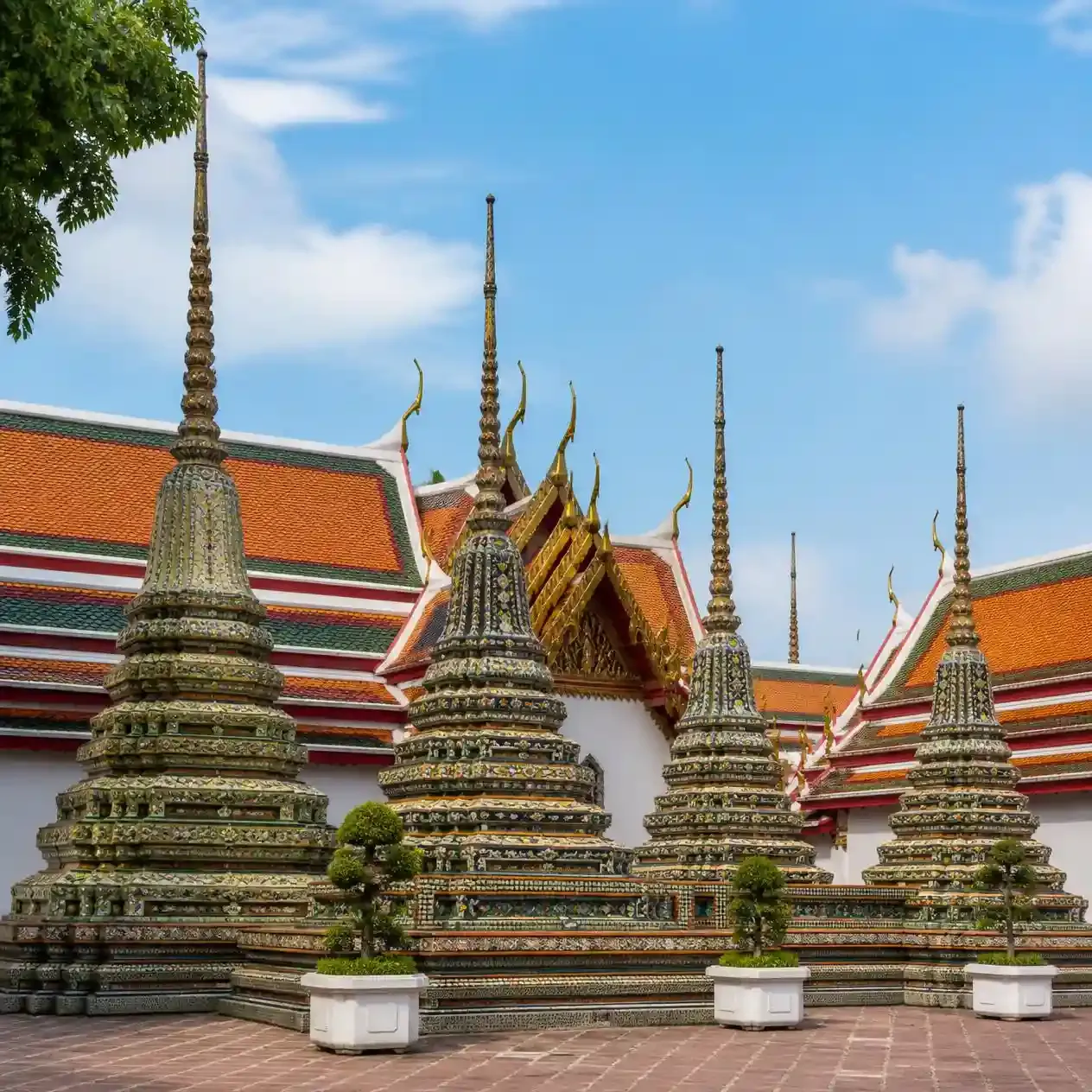 The four tiled royal chedis of Phra Maha Chedi Si Rajakarn rising above the courtyard walls at Wat Pho Bangkok