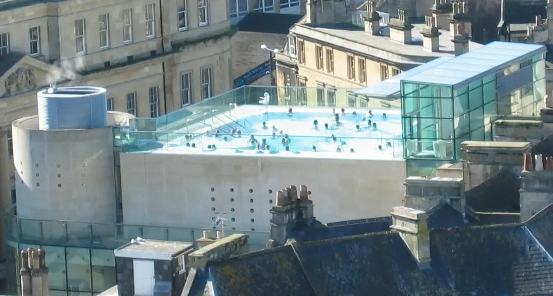 The open-air rooftop thermal pool at Thermae Bath Spa at dusk overlooking the Bath skyline