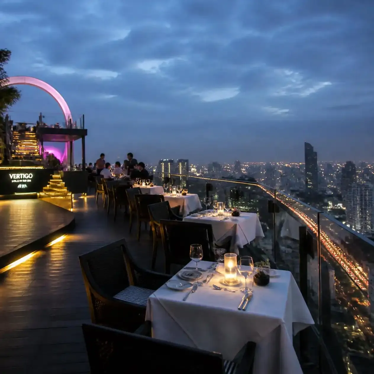 Perimeter dinner tables set along the narrow open-air grill terrace at Vertigo Bangkok on the 61st floor of Banyan Tree