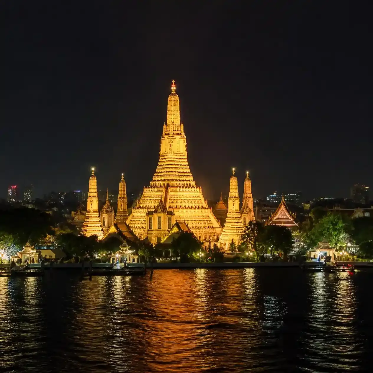 Wat Arun Bangkok illuminated after dark, viewed from the east bank across the Chao Phraya River