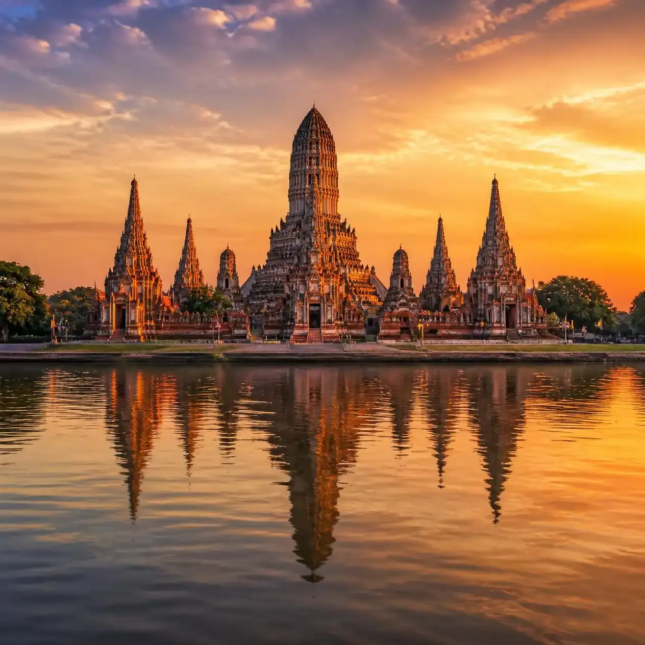 Khmer-style prangs of Wat Chaiwatthanaram reflected in the Chao Phraya river at golden hour during an Ayutthaya day trip from Bangkok