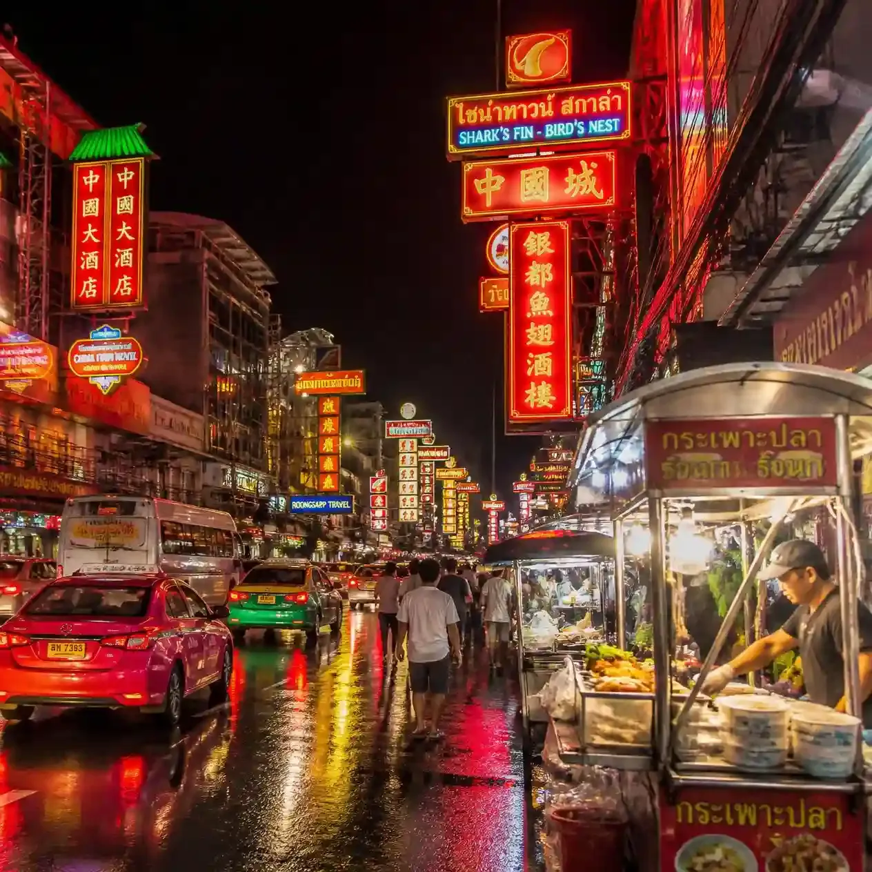 Neon signage glowing above street food carts along Yaowarat Road in Bangkok's Chinatown at night