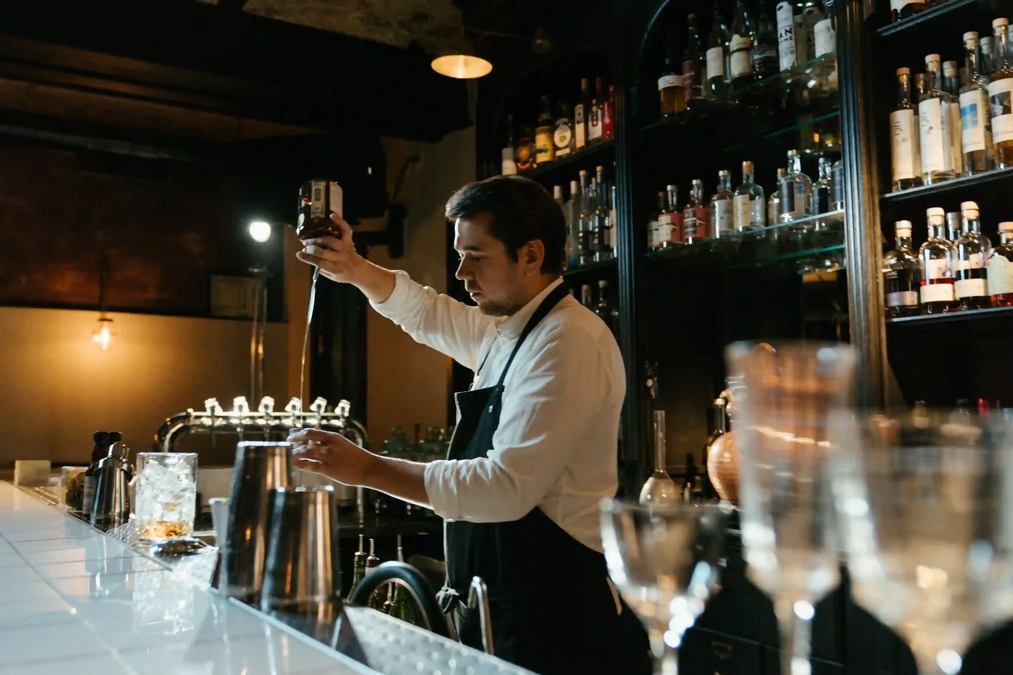 Bartender mixing a cocktail in a dimly lit Shoreditch bar during a London pub crawl