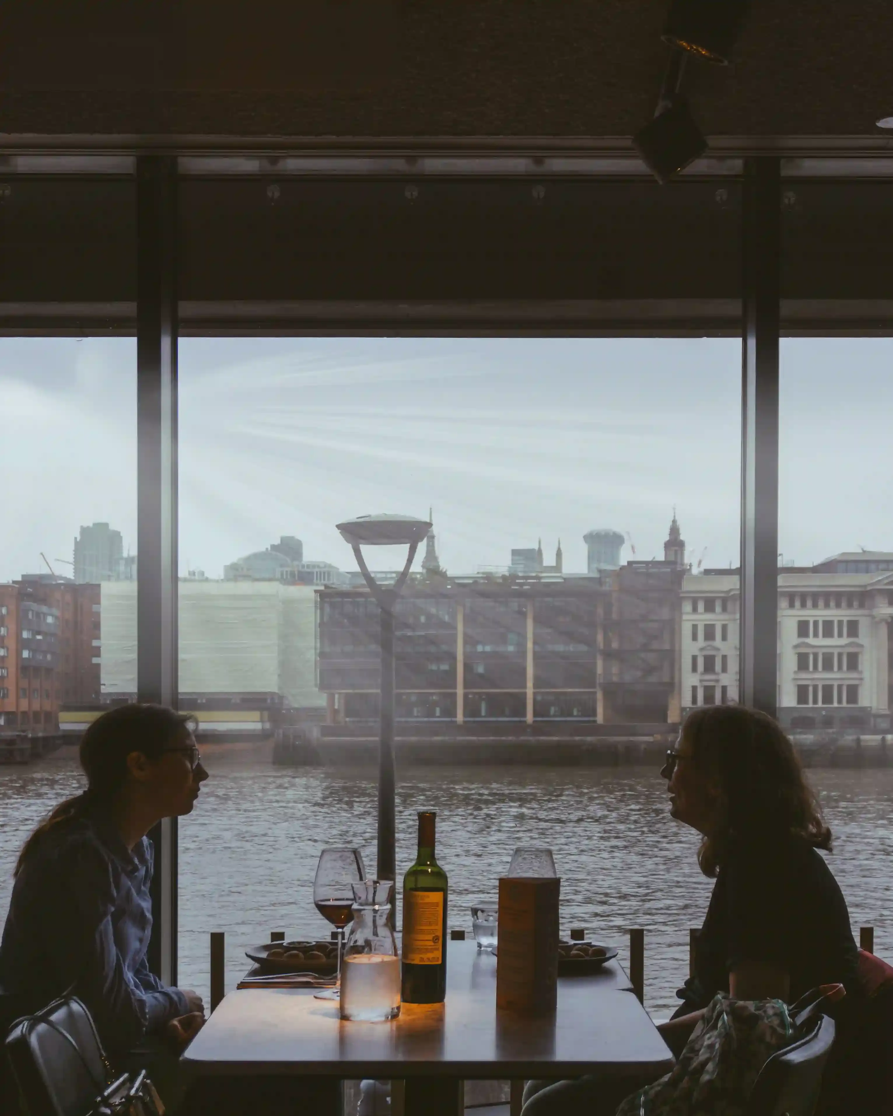 Candlelit dinner table beside a tall window overlooking the illuminated London skyline at night