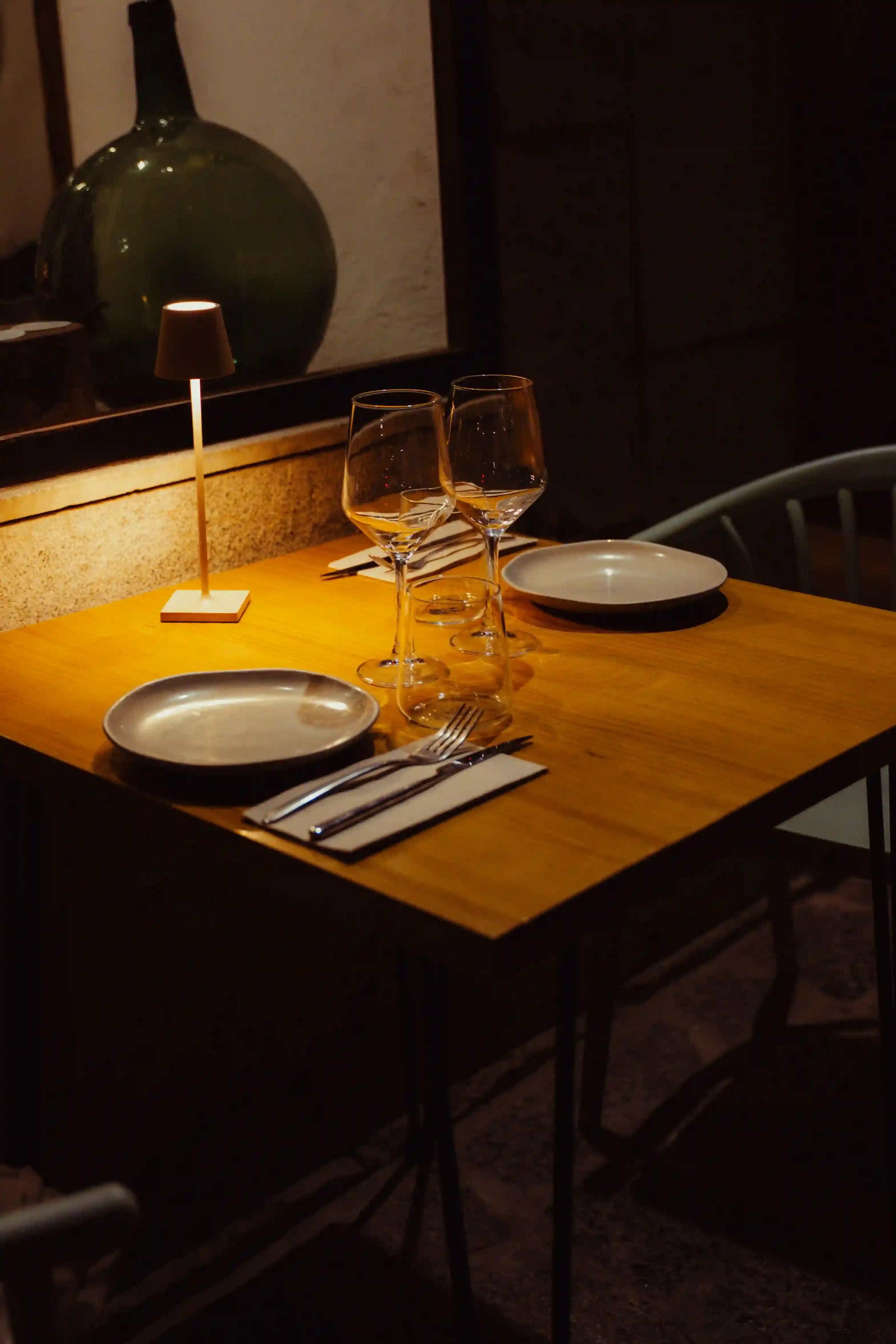 Intimate candlelit table for two set for dinner in a softly lit London restaurant dining room