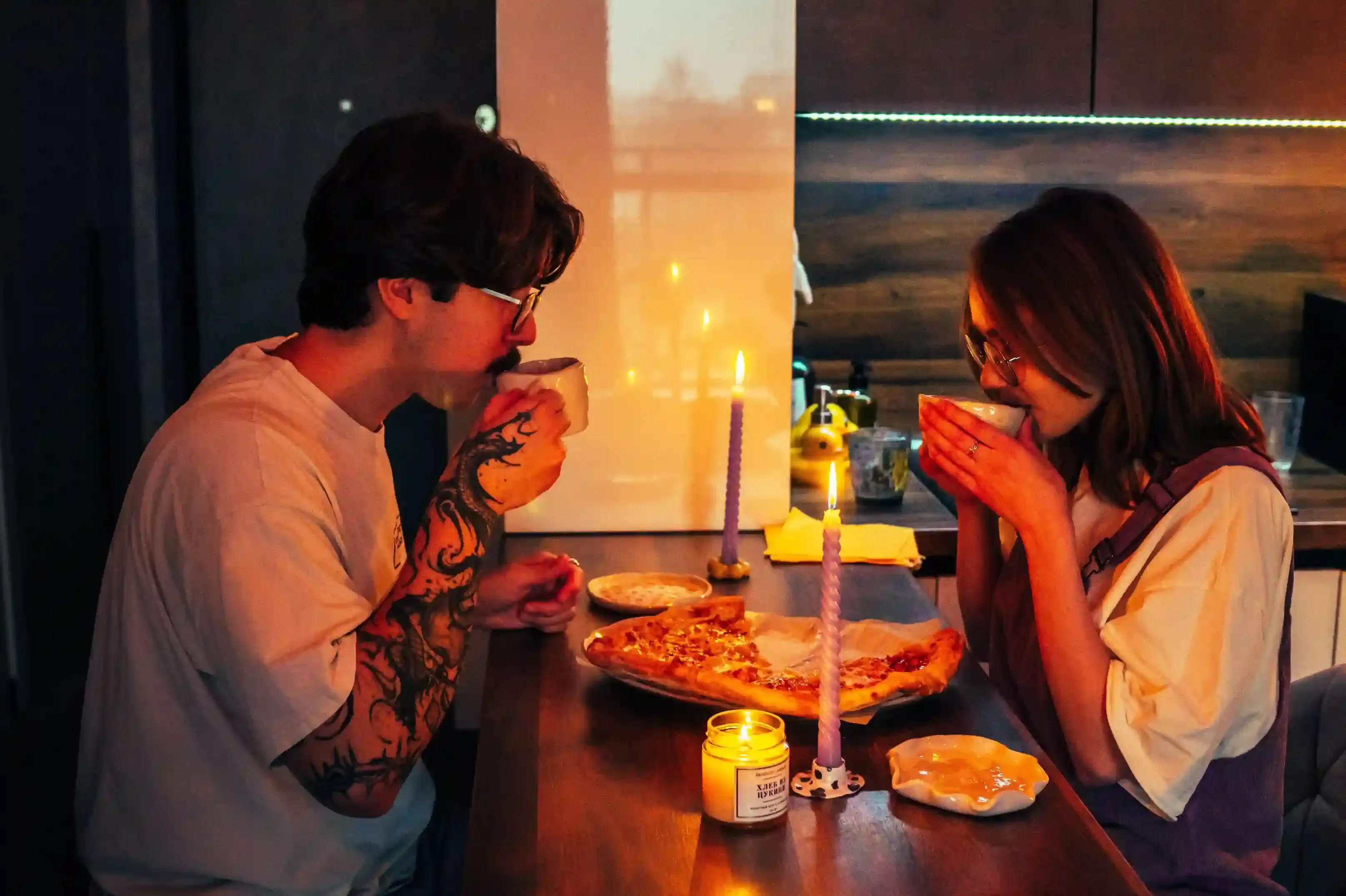 Couple dining at a window table on a Thames dinner cruise at dusk with Tower Bridge illuminated behind them in London