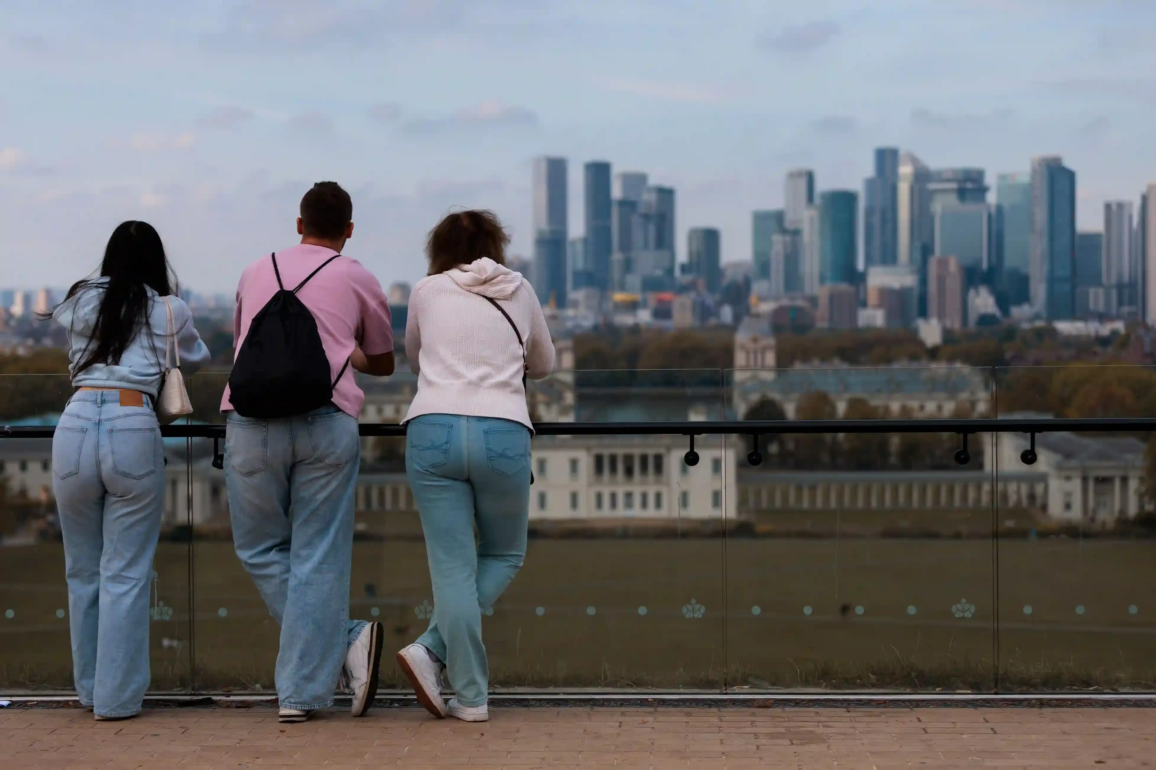 Family on the hilltop in Greenwich Park looking across the London skyline towards Canary Wharf