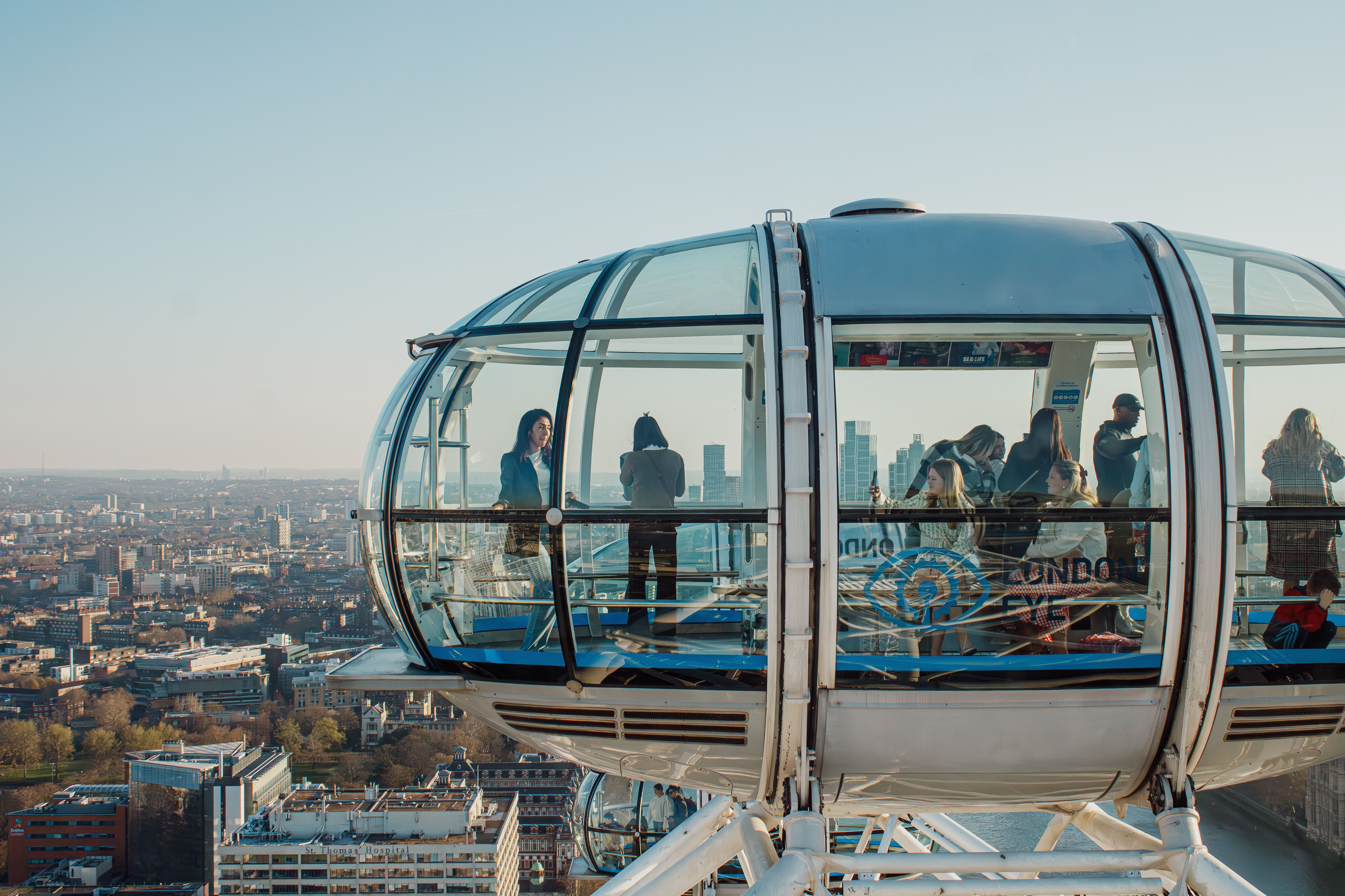 Passengers inside a London Eye glass capsule looking out toward Big Ben and the Houses of Parliament in London
