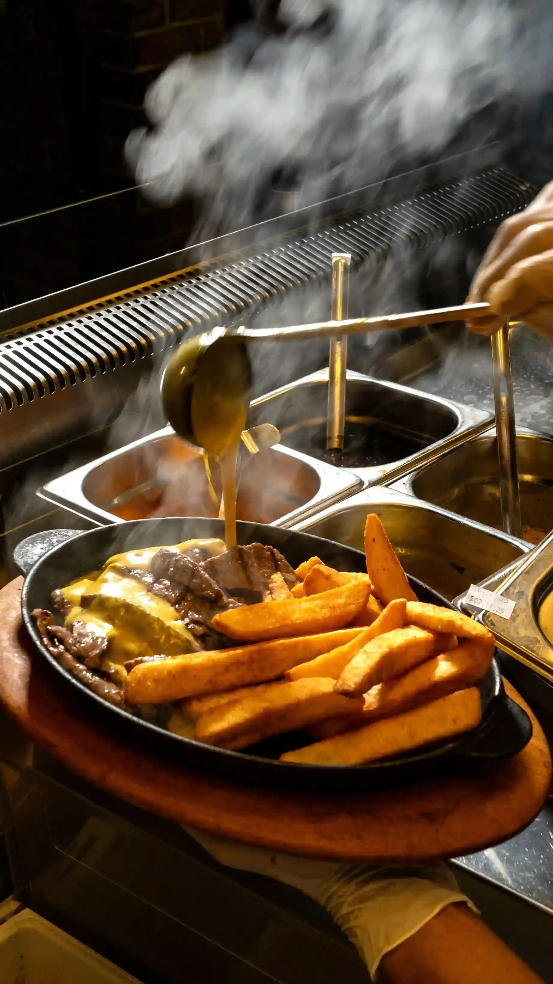 A trader scraping melted raclette cheese over potatoes at the Kappacasein stall in Borough Market Kitchen, London