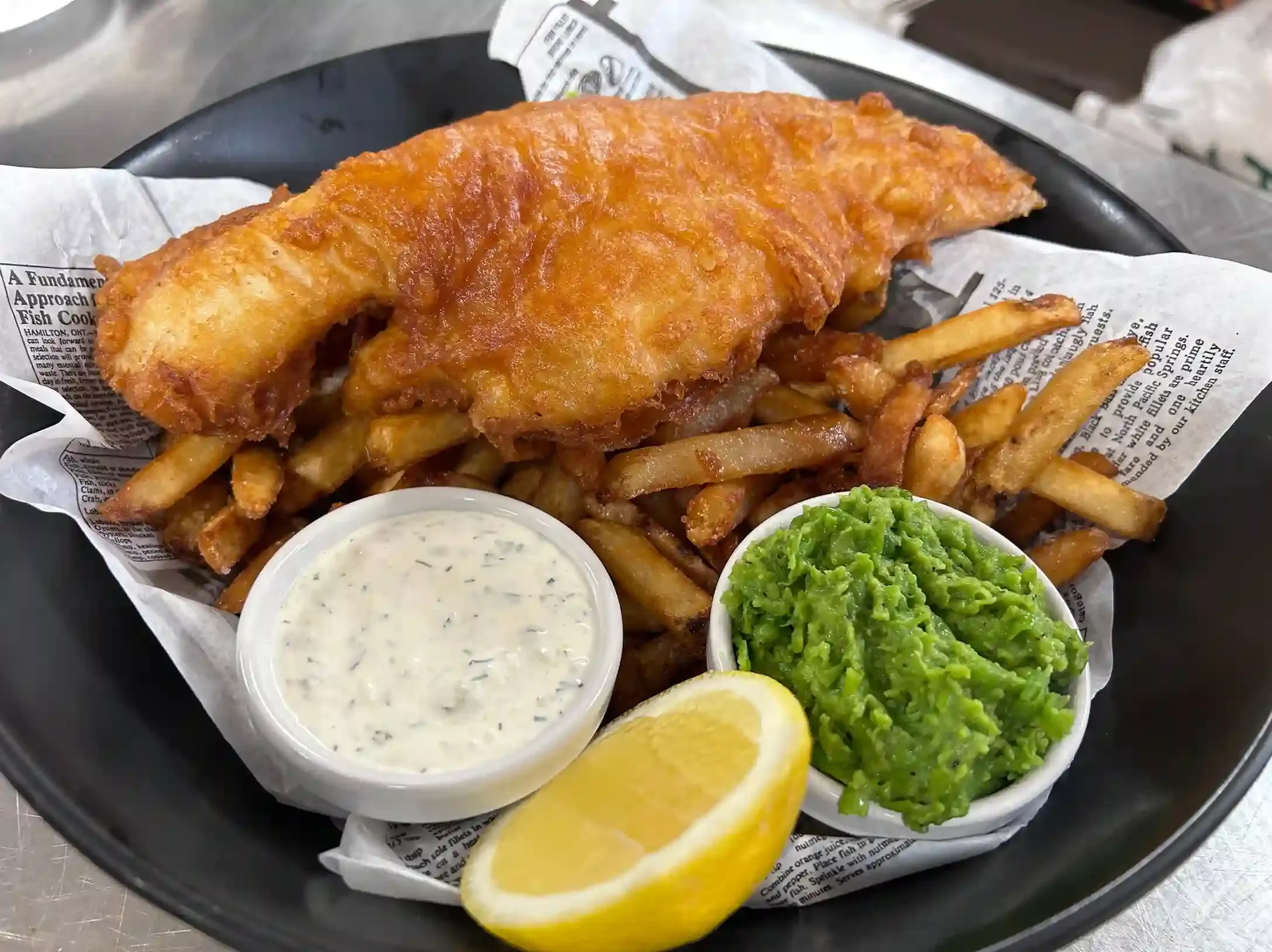Golden battered fish and chips with mushy peas served at a traditional London fish and chip shop
