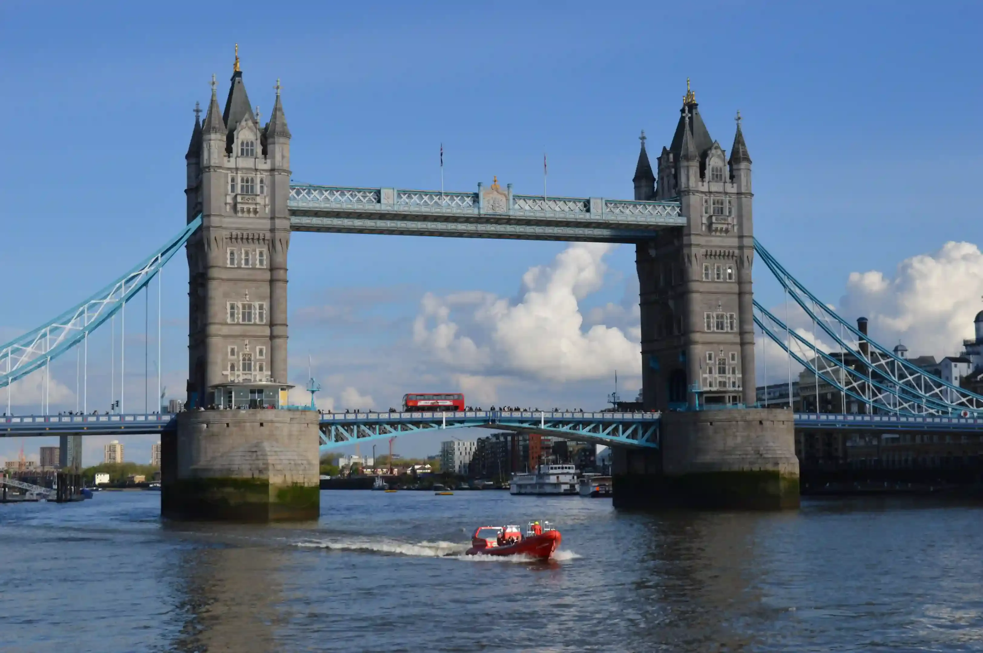 Red Thames speedboat carving a high-speed turn near Tower Bridge during an adventure activity in London